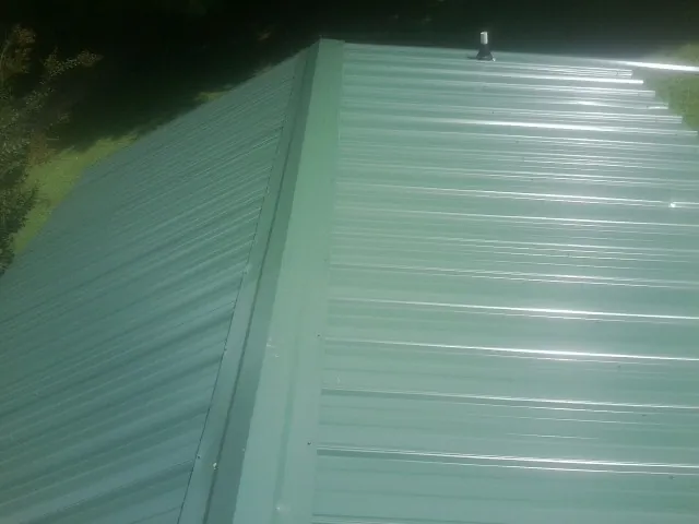 New green metal panels meeting at the ridge of a roof — Flat Roof Repair work by our crew in Lavina