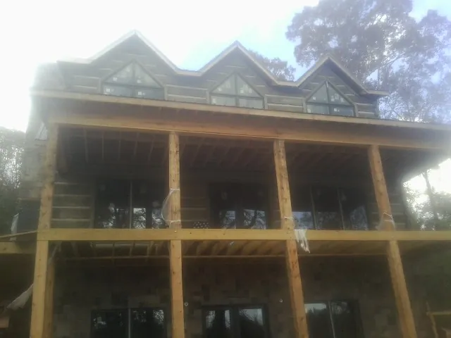 Dormers and porch framing on a large log home under construction — Roof Coating work by our crew in Lavina