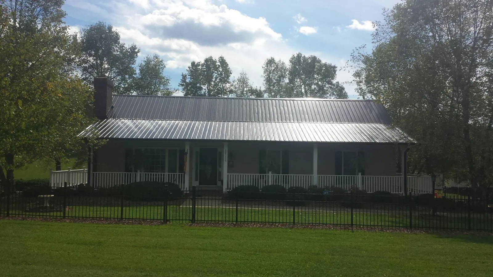 Gray metal roof on a brick ranch with a full width front porch — Gutter Guard Installation work by our crew in Lavina