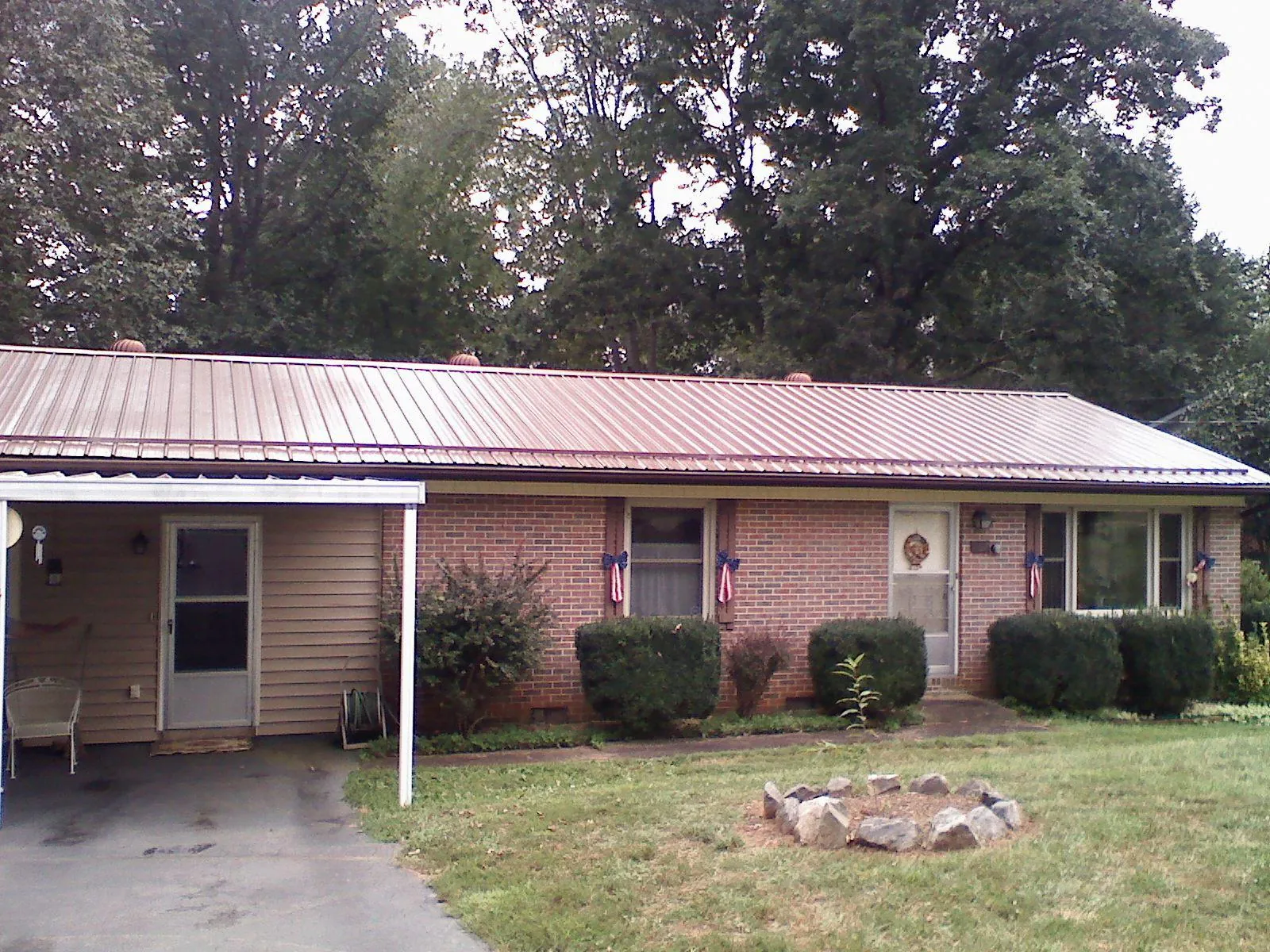 Bronze metal roof and carport on a brick ranch home — Roof Repair work by our crew in Lavina